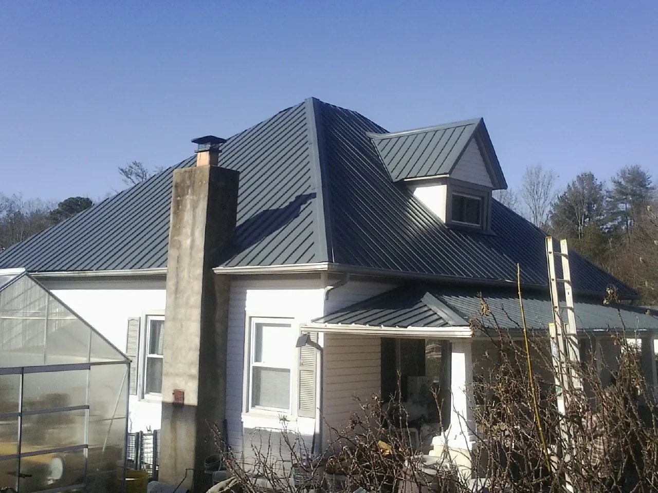 Dark blue standing seam metal roof on a white farmhouse with dormer — Slate & Tile Roof Repair by Roofing Brothers in Perryville