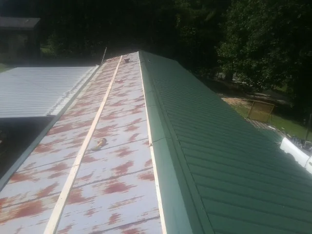 Old rusted panels beside newly installed green metal roofing — Wind Damage Roof Repair by Roofing Brothers in Perryville