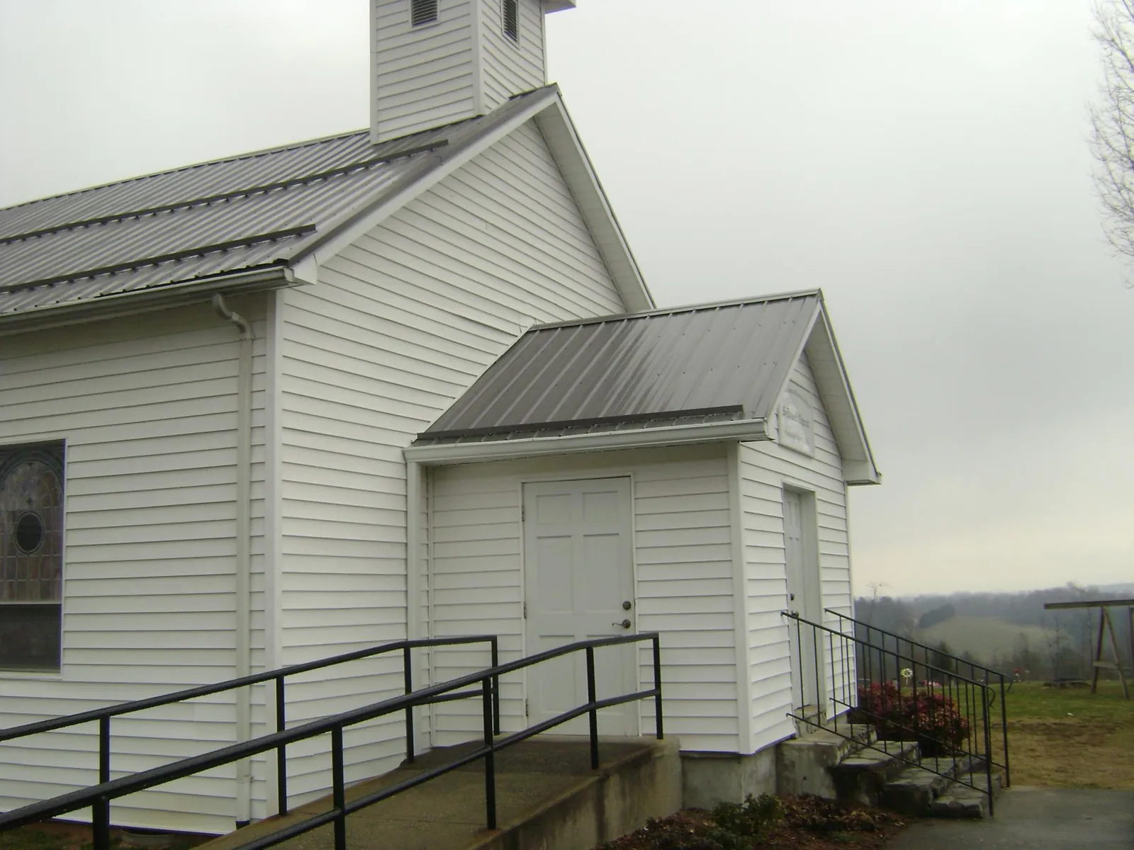 Gray metal roof on a white clapboard church with a steeple in Perryville