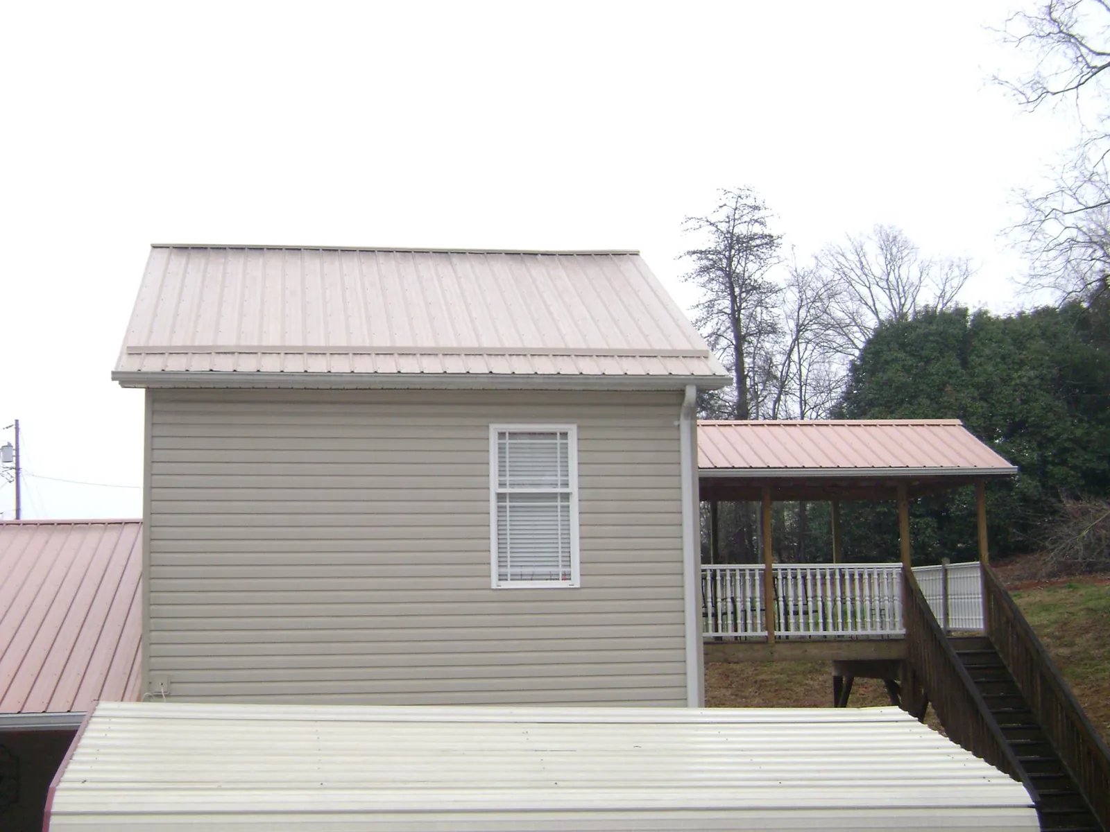 Tan metal roofs on a two story addition and attached porch, from a Roof Replacement job in Perryville