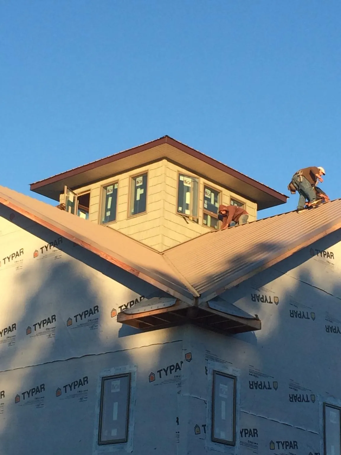 Roofers working around a rooftop cupola on a new metal roof at sunset — Roof Waterproofing in Perryville by Roofing Brothers
